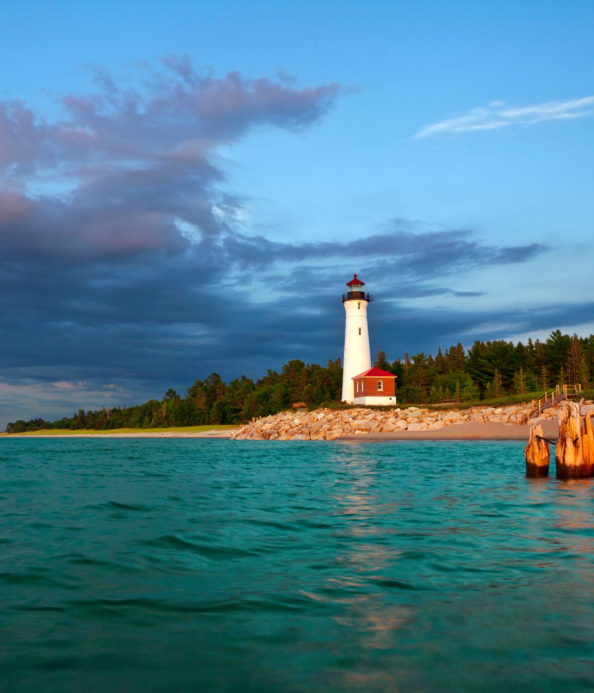Crisp Point Lighthouse white tower with red roof on a remote Lake Superior shoreline in Michigan's Upper Peninsula at sunset.