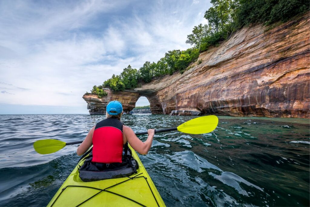 A kayaker paddling along the sandstone cliffs and arches of Pictured Rocks National Lakeshore on Lake Superior in Michigan's Upper Peninsula