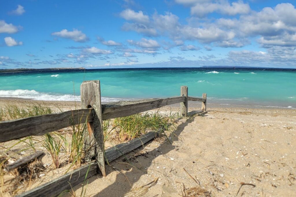 A scenic view of the Lake Michigan coastline along the Leelanau Peninsula with blue water and sandy dunes.