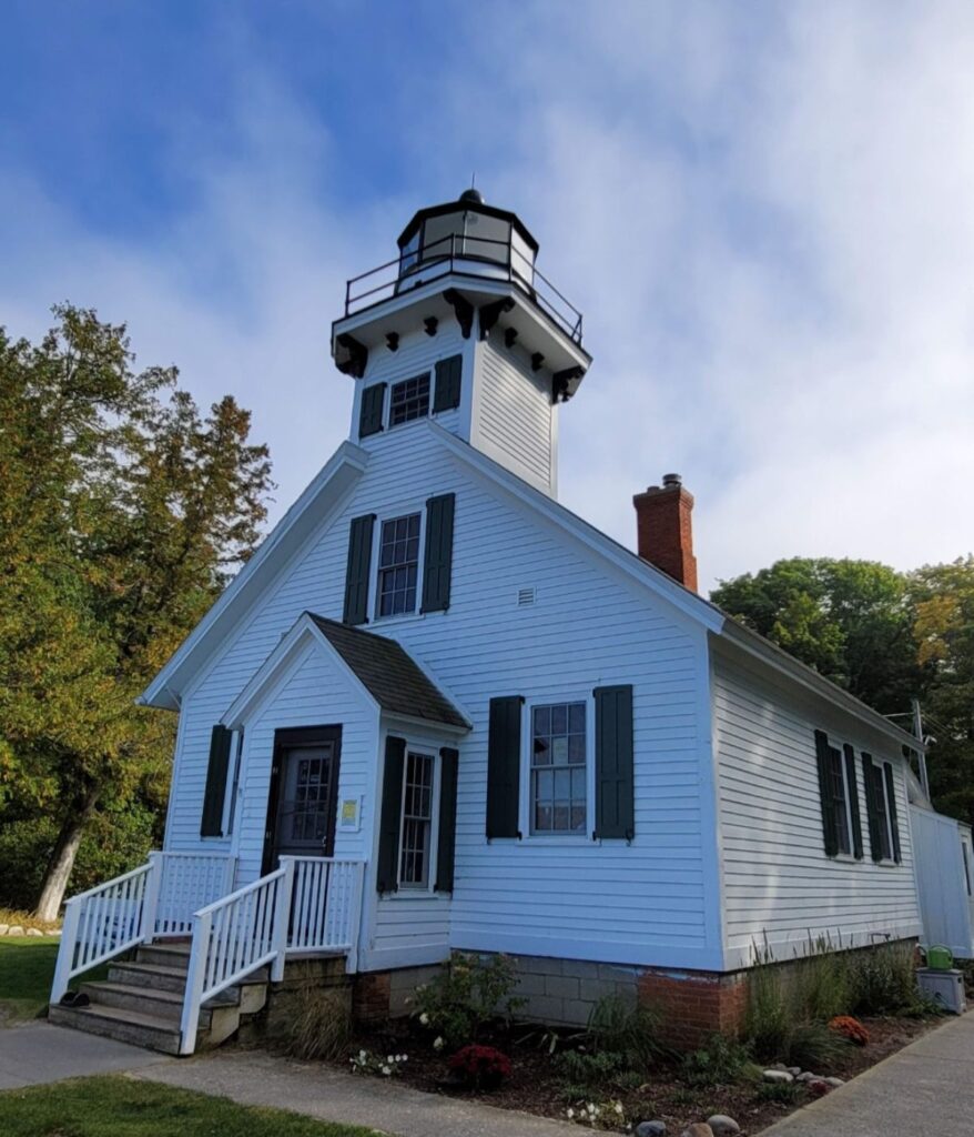 Mission Point Lighthouse white wood schoolhouse-style tower with green shutters at the tip of Old Mission Peninsula near Traverse City.