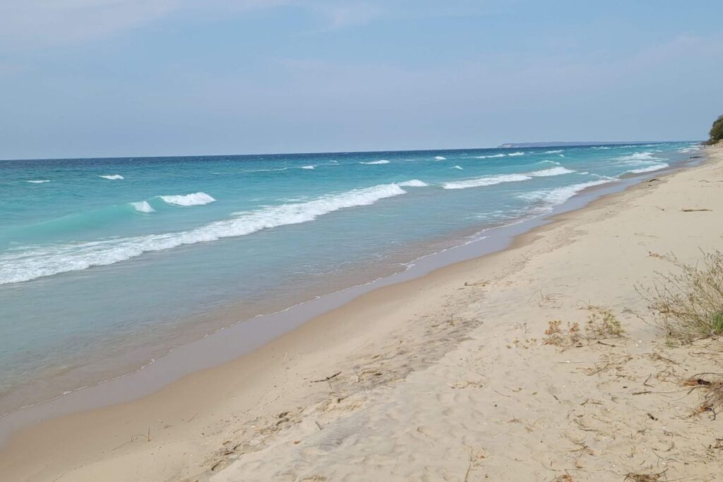 The calm, shallow waters of North Bar Lake in Empire, Michigan, separated from Lake Michigan by a low sandy dune.