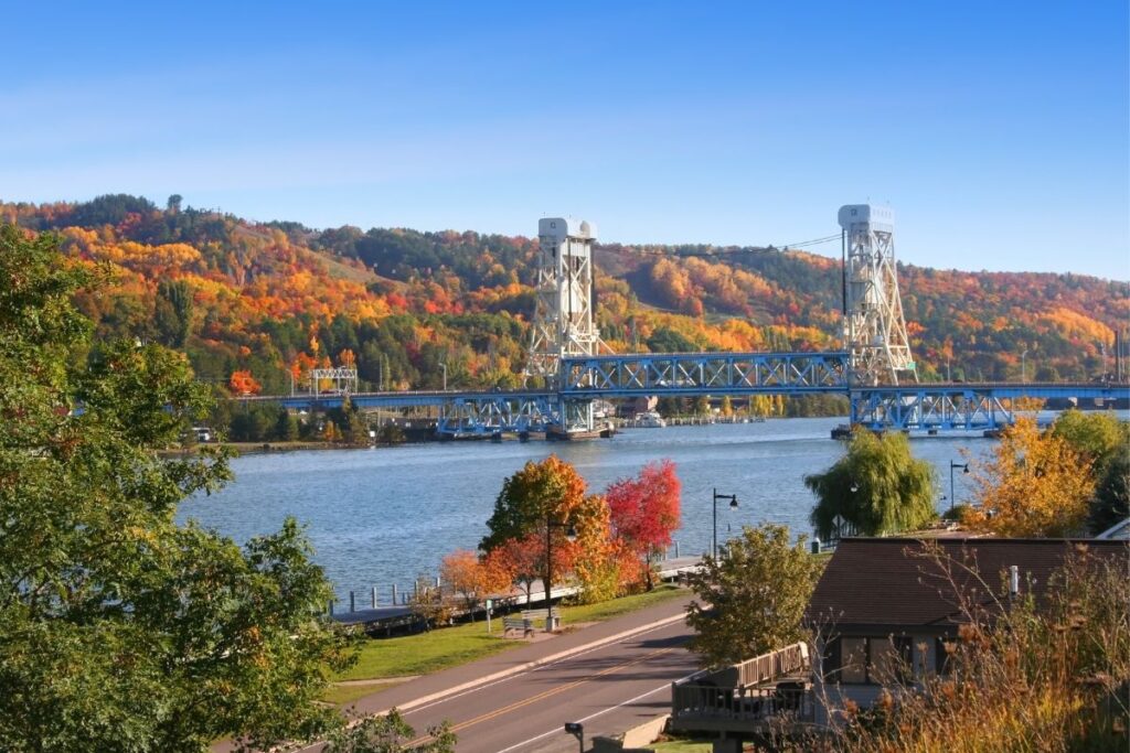The Portage Lake Lift Bridge connecting Houghton and Hancock in Michigan's Keweenaw Peninsula, surrounded by peak fall color on the surrounding hillsides