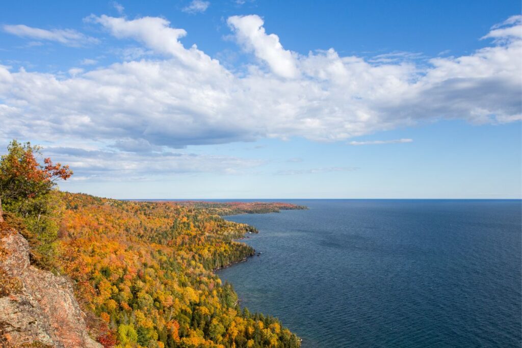 Aerial view of the Michigan Upper Peninsula's Lake Superior shoreline in peak fall color, with rocky cliffs and forested coastline