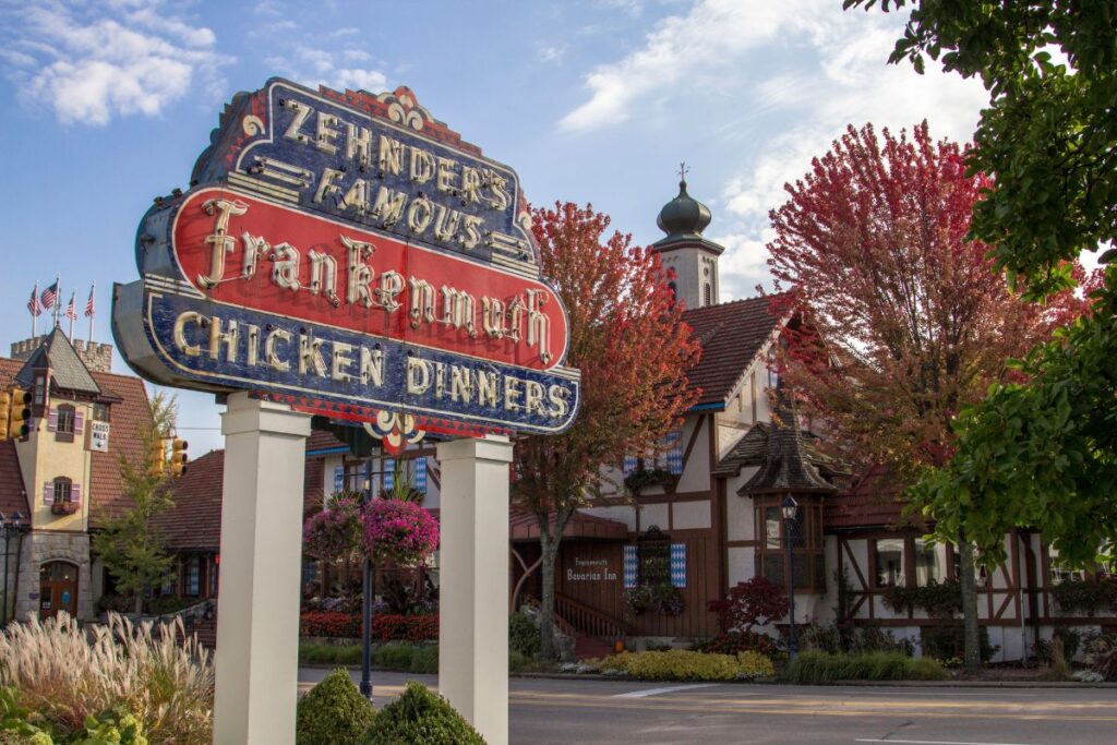 The iconic neon Zehnder's Famous Chicken Dinners sign with the half-timbered Bavarian Inn restaurant behind it in downtown Frankenmuth, Michigan.